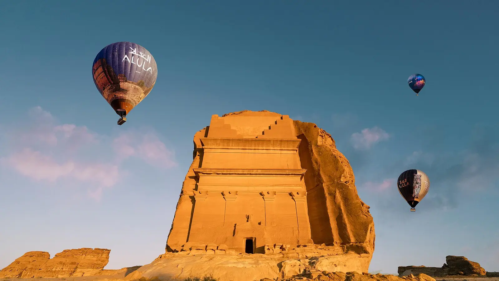 Hot air balloons above a rock-cut Nabatean tomb at Hegra in AlUla